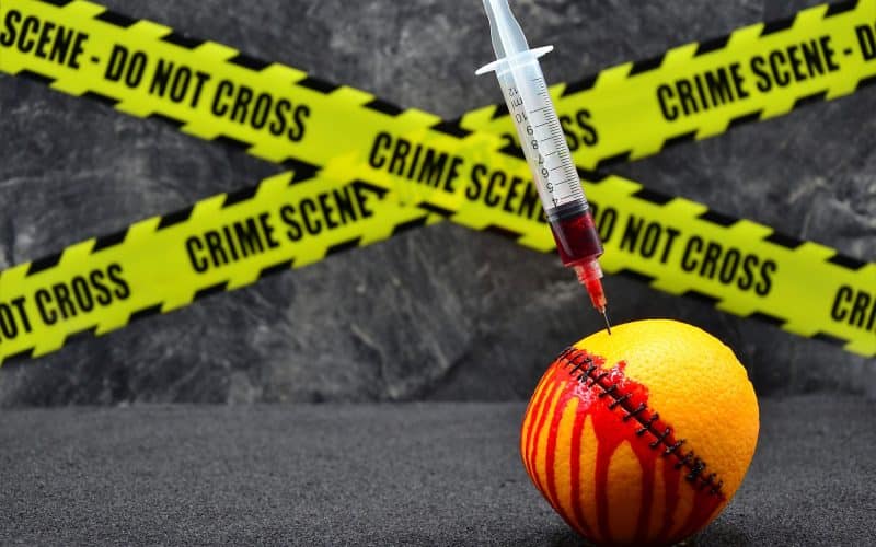 Closeup of a bloody stitched lemon with a syringe on it with warning ribbons on the background